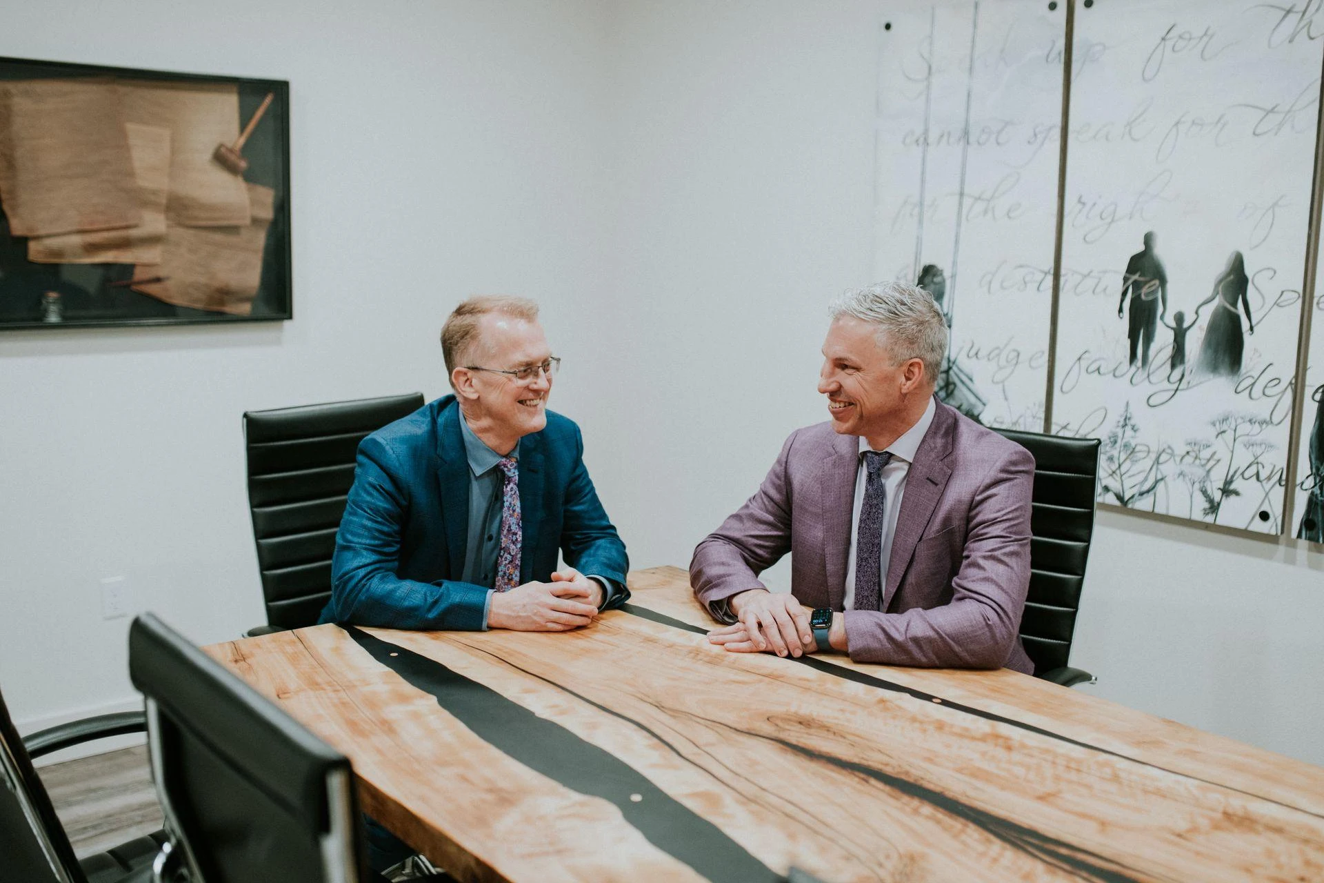 Two team members in conversation around a conference table.